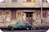 A car protected from the grime of the city by a grimy car cover